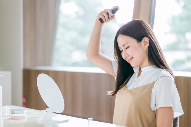 髪にスプレーする女性