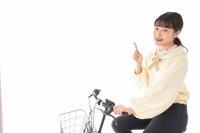 自転車に乗り指を指す女性